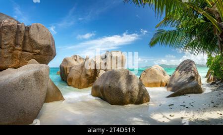 Roches granitiques et palmiers sur la pittoresque plage de sable tropical Anse Source d'argent, île de la Digue, Seychelles Banque D'Images