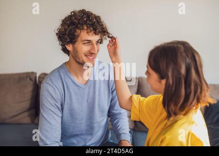 Portrait de jeune couple heureux amoureux. La femme joue avec les cheveux bouclés de l'homme. Banque D'Images