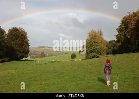 Chichester, West Sussex. 30 octobre 2023. Lara Young (7 ans) regarde un arc-en-ciel entre de fortes averses de pluie à West Dean Gardens à Chichester, dans le Sussex de l'Ouest. Crédit : Katie Collins/Alamy Live News Banque D'Images