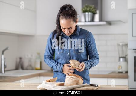 La femme ne peut pas manger du pain et des produits céréaliers à cause de l'intolérance au gluten. Une jeune femme cœliaque souffre de douleurs abdominales après avoir mangé du pain frais. Banque D'Images