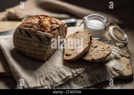 Pain au levain frais avec une tranche coupée et du sel sur une planche à découper. Banque D'Images