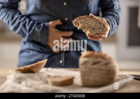 La femme ne peut pas manger du pain et des produits céréaliers à cause de l'intolérance au gluten. Une jeune femme cœliaque souffre de douleurs abdominales après avoir mangé du pain frais. Banque D'Images