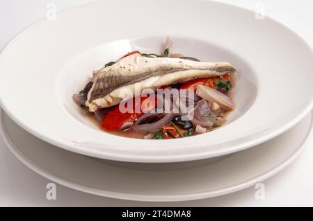 Poisson blanc sur un lit de tomatos et d'oignons Banque D'Images