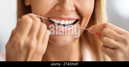Soins bucco-dentaires. Gros plan photo de souriante mature femelle utilisant Dental Floss Banque D'Images