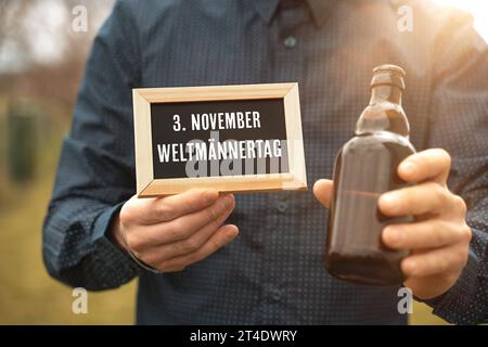 29 Oktober 2023 : Tafel mit Gruß zum Weltmännertag am 3 novembre hält ein Mann mit einer Bierflasche in der Hand FOTOMONTAGE *** Conseil avec salutation pour la Journée mondiale des hommes le 3 novembre tient un homme avec une bouteille de bière dans sa main PHOTOMONTAGE crédit : Imago/Alamy Live News Banque D'Images