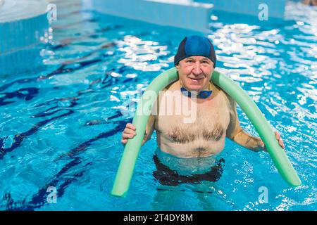 homme retraité en maillot de bain et lunettes de protection s'exerçant dans la piscine intérieure moderne. Photo de haute qualité Banque D'Images