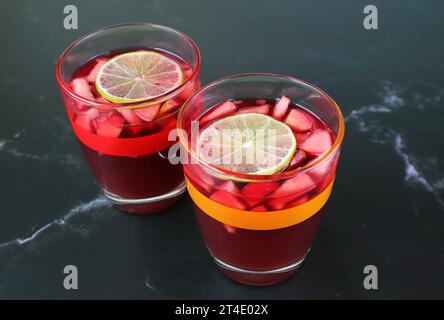 Gros plan deux verres de vin rouge glacé Sangria isolé sur table en marbre noir Banque D'Images