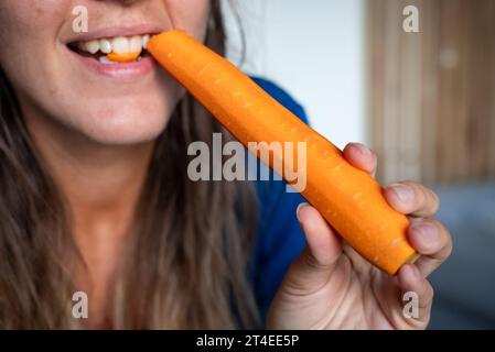La femme mange de la nourriture. La femme mange de la carotte. Plan rapproché d'une fille mangeant des carottes. Visage tout en mangeant carotte. Banque D'Images