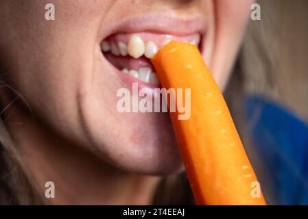 La femme mange de la nourriture. La femme mange de la carotte. Plan rapproché d'une fille mangeant des carottes. Visage tout en mangeant carotte. Banque D'Images