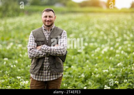 Agriculteur ou agronome utilise la tablette numérique pour analyser et vérifier la croissance et la maladie des plantes en fleurs dans le champ de pommes de terre. Technologie agricole intelligente Banque D'Images