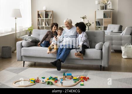 Rire famille multigénérationnelle passer du temps à la maison en utilisant un smartphone Banque D'Images