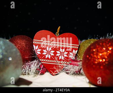 Jouet d'arbre de Noël sous la forme d'un cœur entouré de boules de Noël multicolores et de guirlande du nouvel an sur le fond d'une imitation de Banque D'Images
