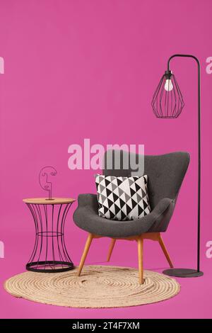 Fauteuil noir avec lampe, table et tapis sur fond violet Banque D'Images