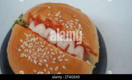 nourriture malsaine, restauration rapide, un hamburger est un pain rempli de viande, légumes, oignon et garni de mayonnaise et sauce chili Banque D'Images