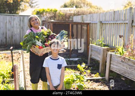 Portrait de grand-mère biracial et petit-fils tenant le panier avec jardin de légumes, espace de copie Banque D'Images