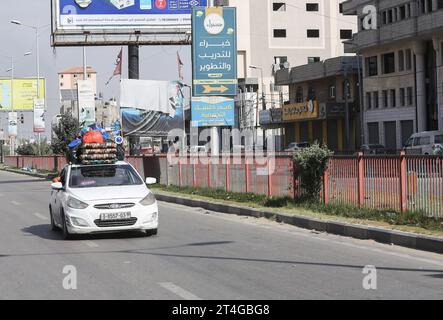 Gaza, Palestine. 30 octobre 2023. Les Palestiniens conduisent une voiture chargée d’effets personnels tandis que de la fumée coule en arrière-plan alors qu’ils fuient le camp de réfugiés de Nuseirat, dans le centre de la bande de Gaza, au milieu des combats en cours entre Israël et le groupe palestinien Hamas. Des milliers de civils, Palestiniens et Israéliens, sont morts depuis le 7 octobre 2023, après que des militants palestiniens du Hamas basés dans la bande de Gaza sont entrés dans le sud d’Israël dans une attaque sans précédent déclenchant une guerre déclarée par Israël au Hamas avec des bombardements de représailles sur Gaza. Crédit : SOPA Images Limited/Alamy Live News Banque D'Images