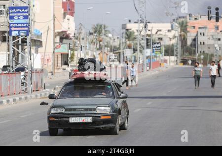 Les Palestiniens conduisent une voiture chargée d’effets personnels tandis que de la fumée coule en arrière-plan alors qu’ils fuient le camp de réfugiés de Nuseirat, dans le centre de la bande de Gaza, au milieu des combats en cours entre Israël et le groupe palestinien Hamas. Des milliers de civils, Palestiniens et Israéliens, sont morts depuis le 7 octobre 2023, après que des militants palestiniens du Hamas basés dans la bande de Gaza sont entrés dans le sud d’Israël dans une attaque sans précédent déclenchant une guerre déclarée par Israël au Hamas avec des bombardements de représailles sur Gaza. (Photo Ahmed Zakot/SOPA Images/Sipa USA) Banque D'Images