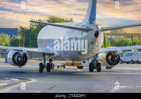 L'avion exécute une opération de refoulement à l'aéroport. Service aérien pour les vols avant le départ le soir au coucher du soleil. Banque D'Images