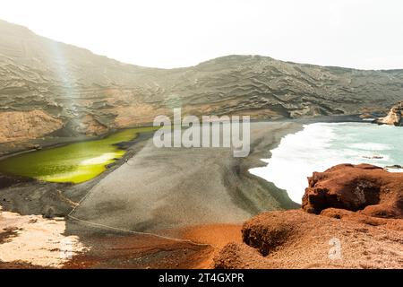 Côte sur l'île de Lanzarote. Un banc de sable volcanique entre l'océan et un petit lac. Banque D'Images