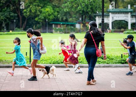 Enfants en train de jouer en courant dans Rizal Park, Ermita, Manille, Philippines. Banque D'Images