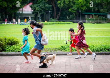 Enfants en train de jouer en courant dans Rizal Park, Ermita, Manille, Philippines. Banque D'Images