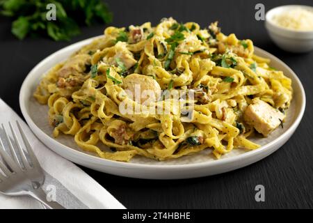 Bacon de poulet crémeux pesto Pasta sur une assiette sur un fond noir, vue de côté. Banque D'Images