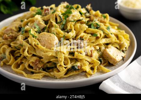 Bacon de poulet crémeux pesto Pasta sur une assiette sur un fond noir, vue de côté. Banque D'Images