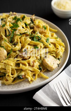 Bacon de poulet crémeux pesto Pasta sur une assiette sur un fond noir, vue de côté. Banque D'Images