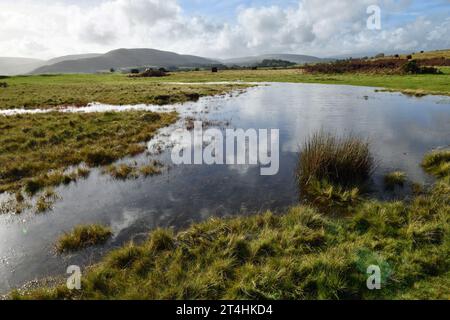 Un grand étang sur Mynydd Illtyd Common dans le comté de Brecon Beacons Powys avec des nuages réfléchis dans l'eau claire avec le ciel bleu Banque D'Images