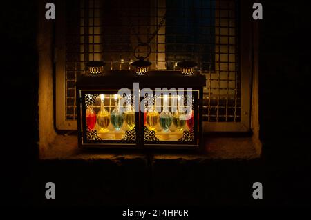 Une menorah Hanukkah utilisant des fioles en verre et des bougies de parafin colorées brûle brillamment dans une boîte de fenêtre à Jérusalem pendant la célébration du Festival o Banque D'Images