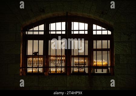 Les menorahs lumineuses de Hanukkah brûlent brillamment avec huit bougies dans une fenêtre arquée lors de la dernière nuit de la célébration de la fête des lumières à Jeru Banque D'Images