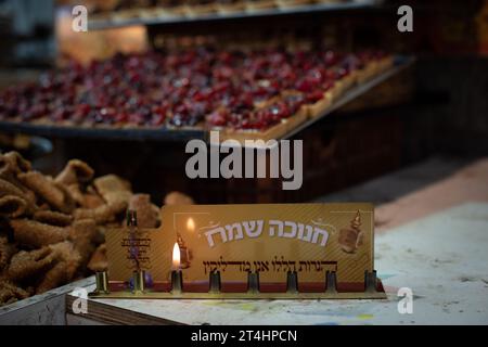 Une seule petite flamme reste allumée dans une menorah de Hanukkah portant les mots hébreux « Happy Hanukkah », « ces bougies sont sacrées » et « Merci et P. Banque D'Images