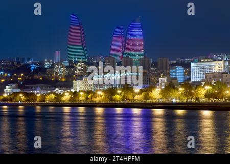 Tours de flamme la nuit à Bakou, Azerbaïdjan. Bâtiments modernes illuminés de couleurs de drapeau d'Azerbaïdjan avec horizon moderne et promenade sur la mer Caspienne. Banque D'Images