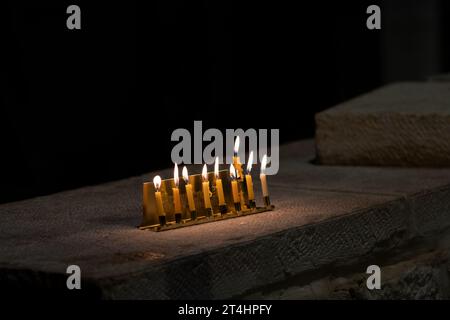 Une petite menorah Hanukkah dorée portant les mots hébreux « Happy Chanukah » brûle avec huit bougies de cire jaunes la dernière nuit du cele Banque D'Images