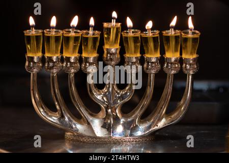 Une menorah Hanukkah argentée avec huit bougies brûle brillamment pendant la célébration de la fête des lumières en Israël. Banque D'Images