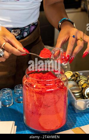 Une directrice de boutique remplit une petite quantité de pigment de couleur pure à l'aide d'une petite cuillère dans un petit pot dans sa boutique d'art à Venise, dans la région vénitienne o Banque D'Images