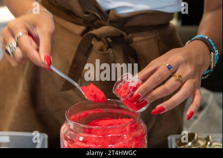 Une directrice de boutique remplit une petite quantité de pigment de couleur pure à l'aide d'une petite cuillère dans un petit pot dans sa boutique d'art à Venise, dans la région vénitienne o Banque D'Images