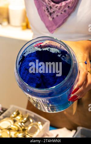 Une directrice de boutique remplit une petite quantité de pigment de couleur pure à l'aide d'une petite cuillère dans un petit pot dans sa boutique d'art à Venise, dans la région vénitienne o Banque D'Images