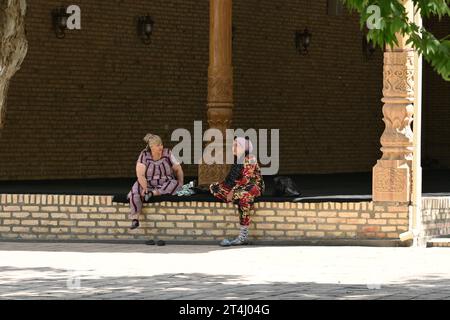 Deux femmes ouzbèkes assises et parlant dans la cour d'une mosquée à Shahrisabz, Ouzbékistan Banque D'Images