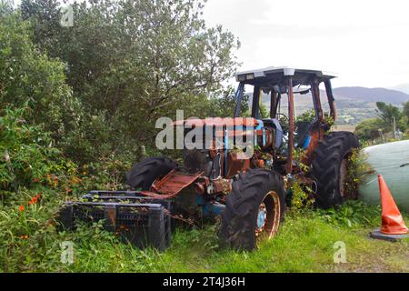 Vieux tracteur rouillé défectueux dans une cour de ferme Banque D'Images
