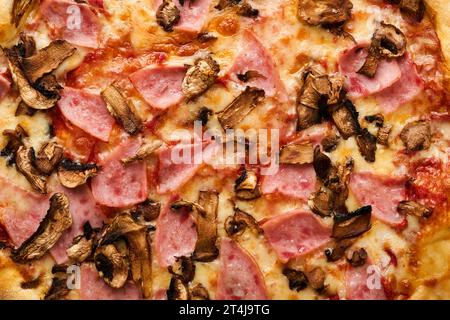 Texture de la nourriture de pizza. Pizza traditionnelle au bacon avec jambon, champignons et fond de fromage. Cuisine traditionnelle italienne. Vue de dessus. Maquette. Banque D'Images