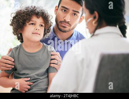 Un avis professionnel est nécessaire. un petit garçon examiné par un médecin méconnaissable pendant que son père le tient. Banque D'Images