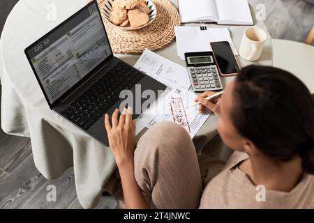 Portrait à angle élevé de jeune femme noire faisant des impôts à la maison et utilisant un ordinateur portable gérant le ménage Banque D'Images