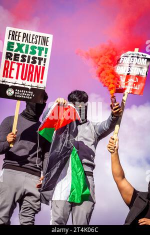 Les manifestants brandissent le drapeau de la Palestine et une fusée éclairante lors de la manifestation pro-palestinienne à Trafalgar Square Banque D'Images