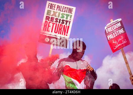 Les manifestants brandissent le drapeau de la Palestine et une fusée éclairante lors de la manifestation pro-palestinienne à Trafalgar Square Banque D'Images