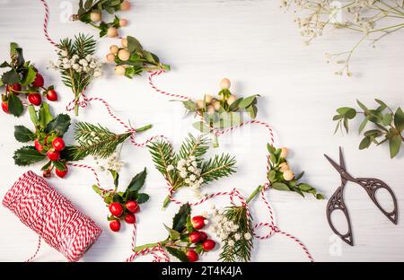 Faire des guirlandes de Noël naturelles avec des fleurs fraîches, des feuilles, des baies et des branches de sapin. Banque D'Images