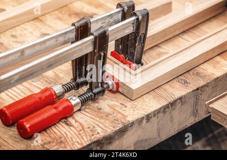Les pinces de charpentier sont fixées aux planches. Collage de menuiserie dans l'atelier Banque D'Images