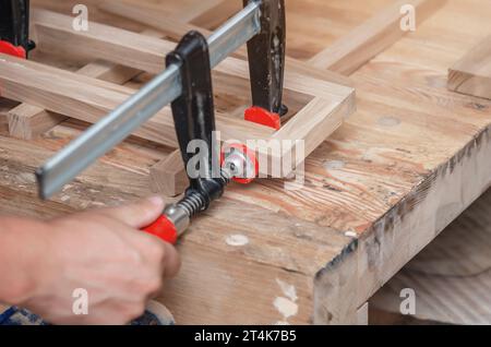 Les pinces de charpentier sont fixées aux planches. Collage de menuiserie dans l'atelier Banque D'Images
