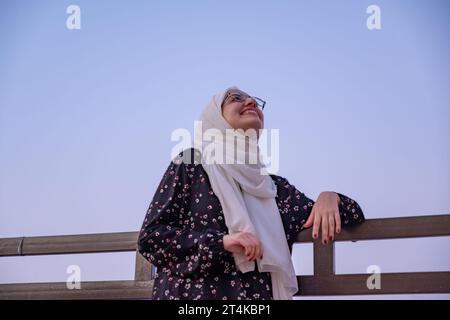 femme portant le hijab et les vêtements islamiques ayant des vacances dans la station avec le sourire sur leur visage et de belles lumières floues en arrière-plan Banque D'Images