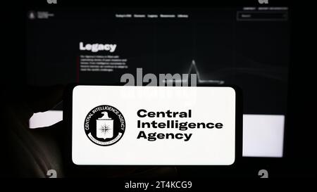 Personne tenant un téléphone portable avec le logo de la Central Intelligence Agency (CIA) des États-Unis devant la page Web. Concentrez-vous sur l'affichage du téléphone. Banque D'Images